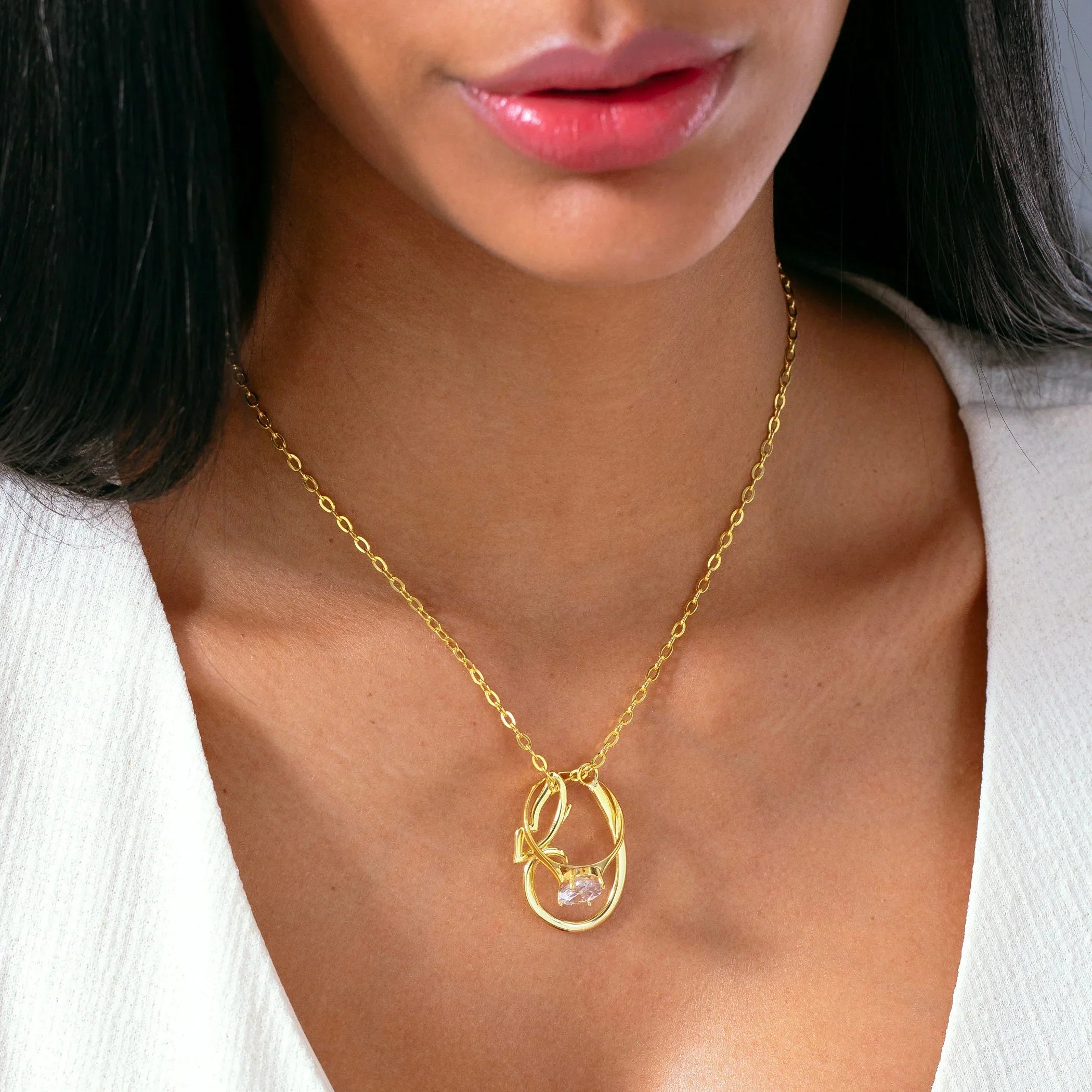 Woman wearing gold necklace with abstract pendant and clear gemstone