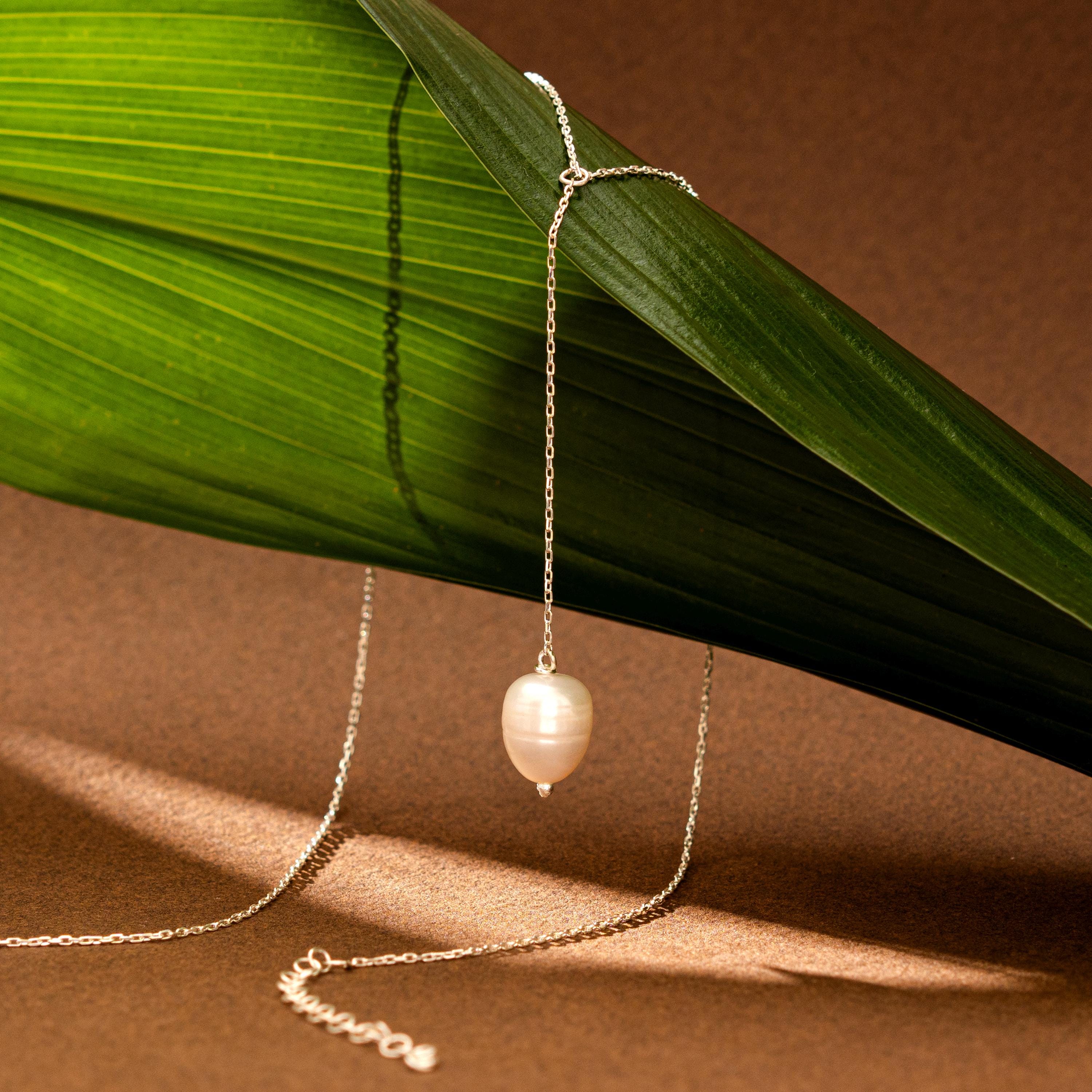 Pearl necklace on a brown surface with a green leaf